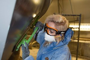 A women in disposable protective workwear works on a car